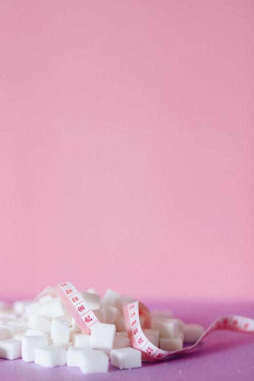 Free Sugar cubes with measuring tape on pink and purple background, symbolizing diet and diabetes. Stock Photo