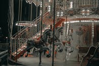 Illuminated carousel with horses in amusement park at night
