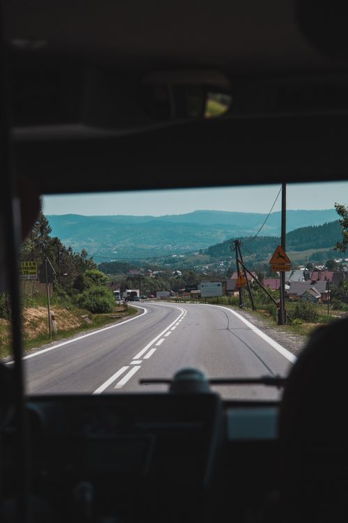Free View of a mountain road from inside a bus, showing scenic countryside and hills. Stock Photo