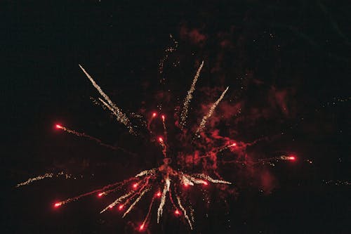 Breathtaking view of illuminated red and golden fireworks bursting into dark cloudless sky at night