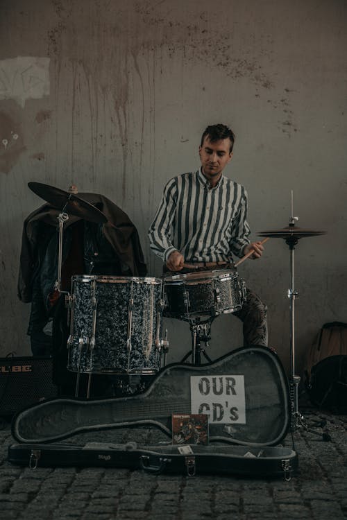 Street musician playing drums near wall