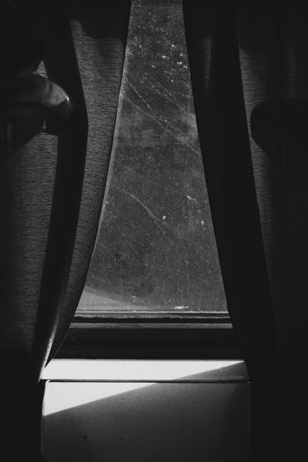 Black and white of dirty window wooden frame and with stains and drapes in room with bright sunlight at home