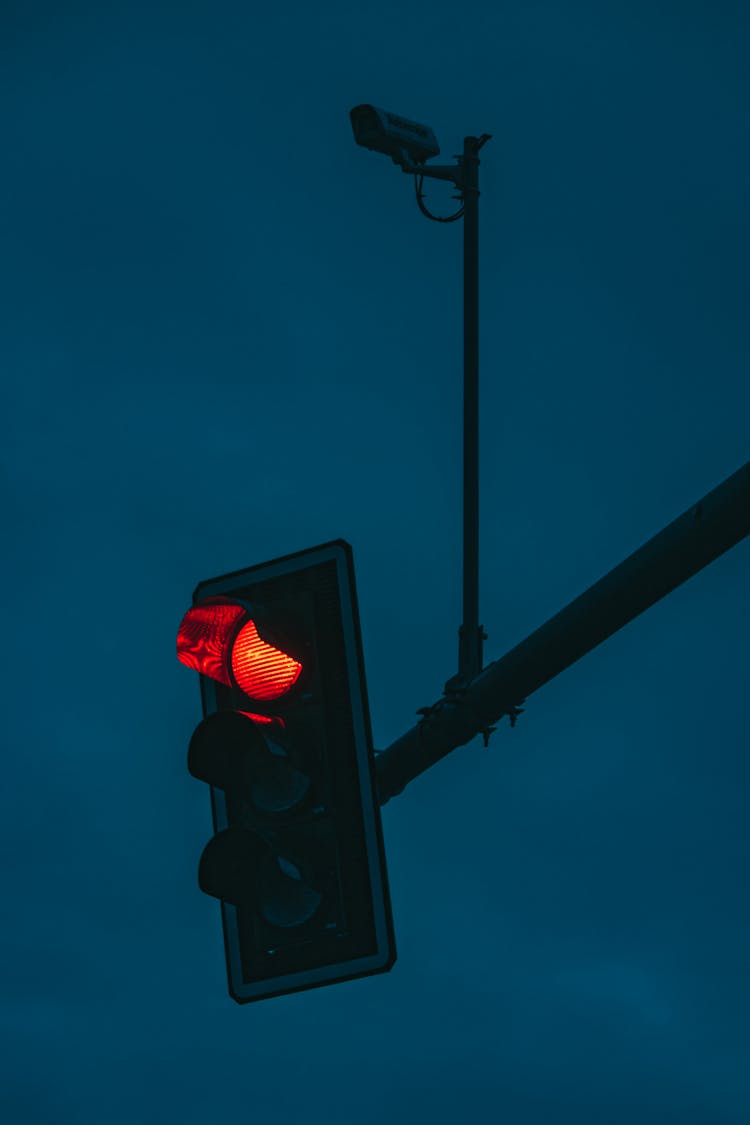 Glowing Red Traffic Light Against Cloudy Night Sky