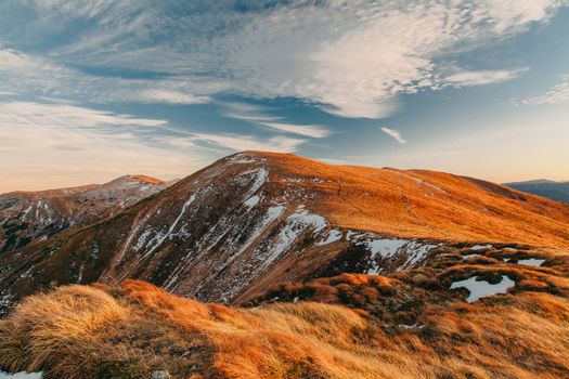 Breathtaking mountain landscape with golden grass and blue sky, captured at sunset.