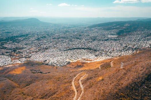 Aerial shot showcasing expansive suburban landscape and mountain roads in Mexico.