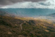 令人惊叹的鸟瞰图，展示了在巨大的云层下穿过山区地形的蜿蜒道路