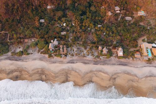 Free Stunning aerial view of a Mexican beachfront with lush greenery and gentle waves. Stock Photo