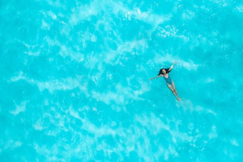 Free Aerial shot of a woman swimming in a clear turquoise sea, capturing serene ocean beauty. Stock Photo