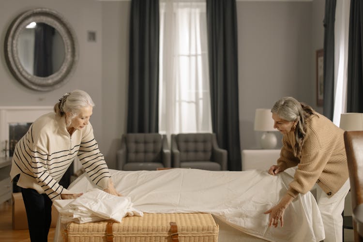 Elderly Women Covering Their Furniture With Cloth