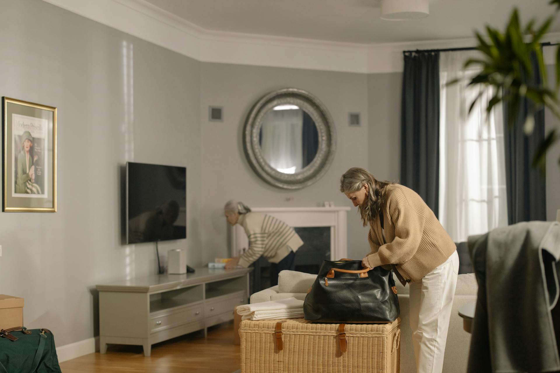 A woman preparing to travel by packing her bag in a stylish, modern living room.