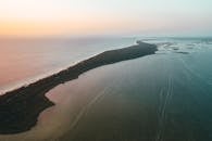 墨西哥海岸线沐浴在温暖的日落色调中的令人惊叹的航拍照片，展示了宁静的水域