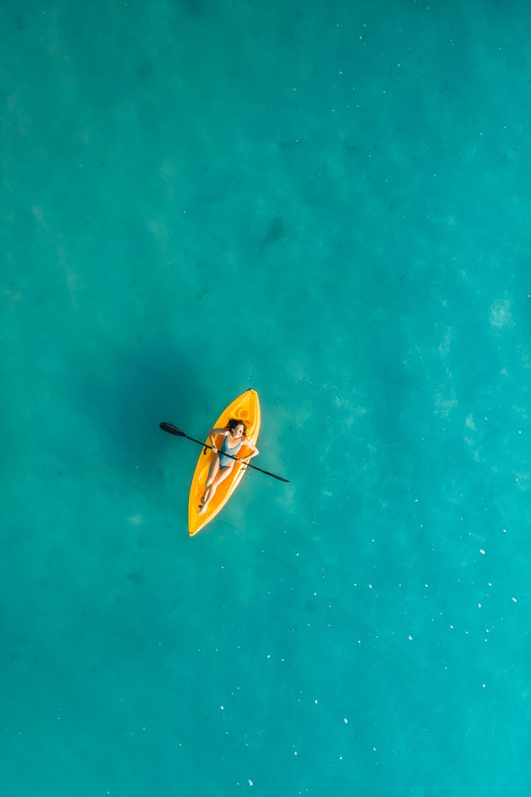 A Woman Lying On A Kayak Board While Holding A Paddleboard