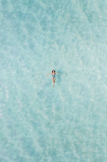 Drone captures serene moment as woman floats in turquoise waters of Bacalar, Mexico.