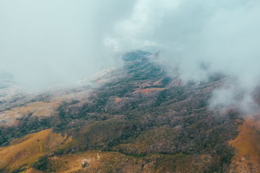 Stunning aerial view of a mountainous landscape shrouded in mist and clouds, emphasizing tranquility.