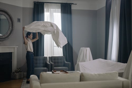 Free A Woman in Denim Jeans Standing while Holding a White Cloth Stock Photo