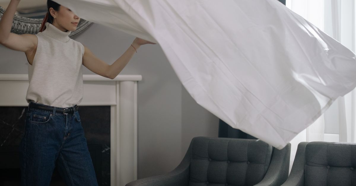 Uma mulher asiática agita uma folha branca dentro de casa, mostrando um estilo de vida e moda modernos.