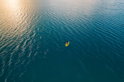 Person Riding Yellow Kayak in the Middle of the Ocean