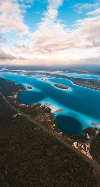 Breathtaking aerial view of a turquoise lagoon amidst lush greenery and a vibrant sunset sky.
