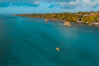 这是一张宁静的航拍照片，拍摄了一名孤独的皮划艇运动员在墨西哥一片充满活力的蓝色湖泊上划船，周围环绕着郁郁葱葱的绿色植物