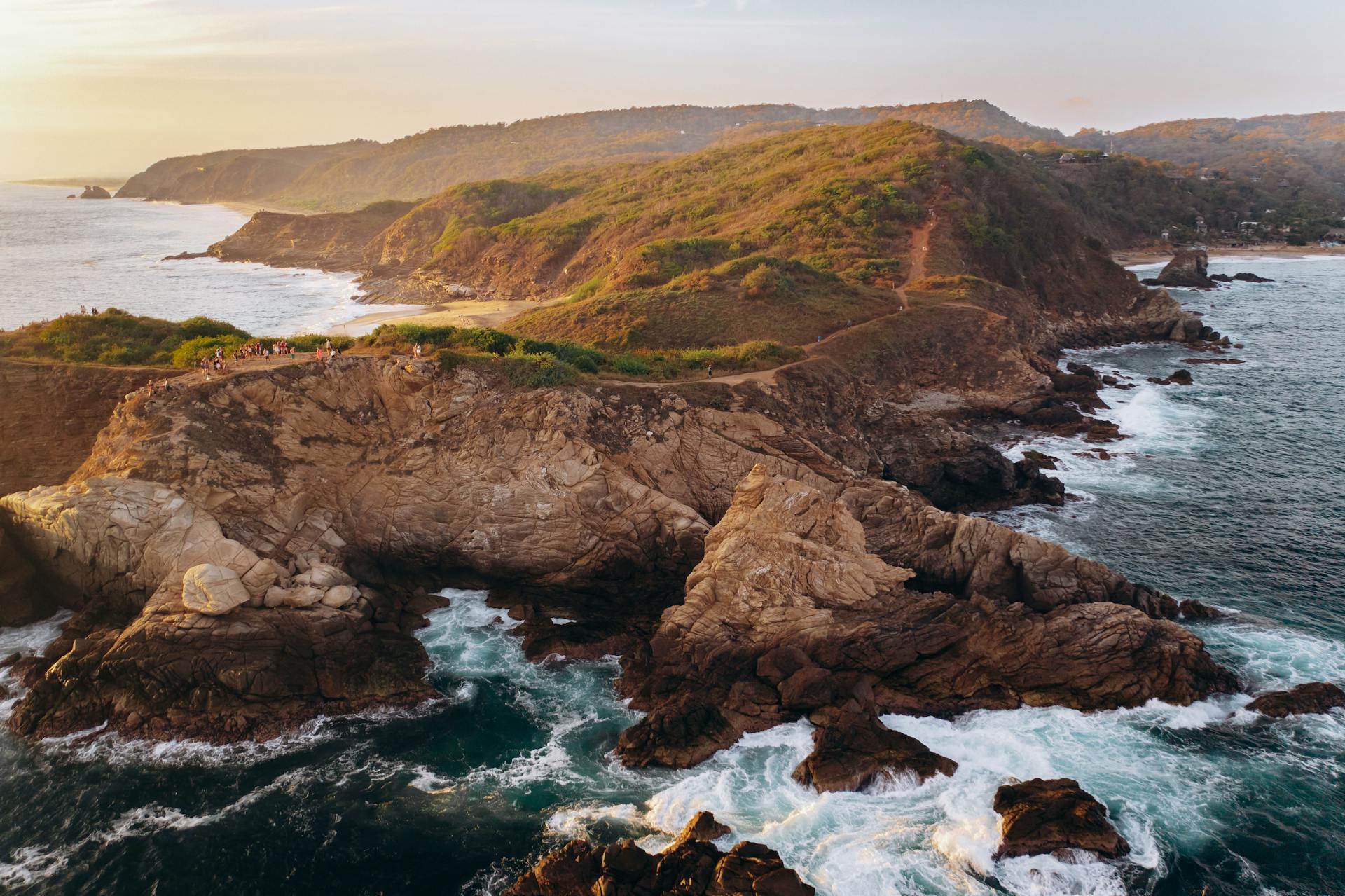 Stunning aerial shot of a rocky Mexican coastline with crashing waves at sunset.