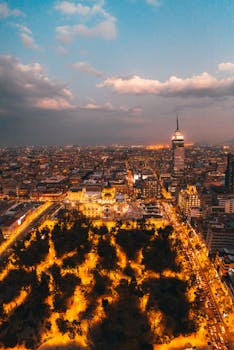 A breathtaking aerial shot of Mexico City featuring iconic landmarks and vibrant city lights at dusk.