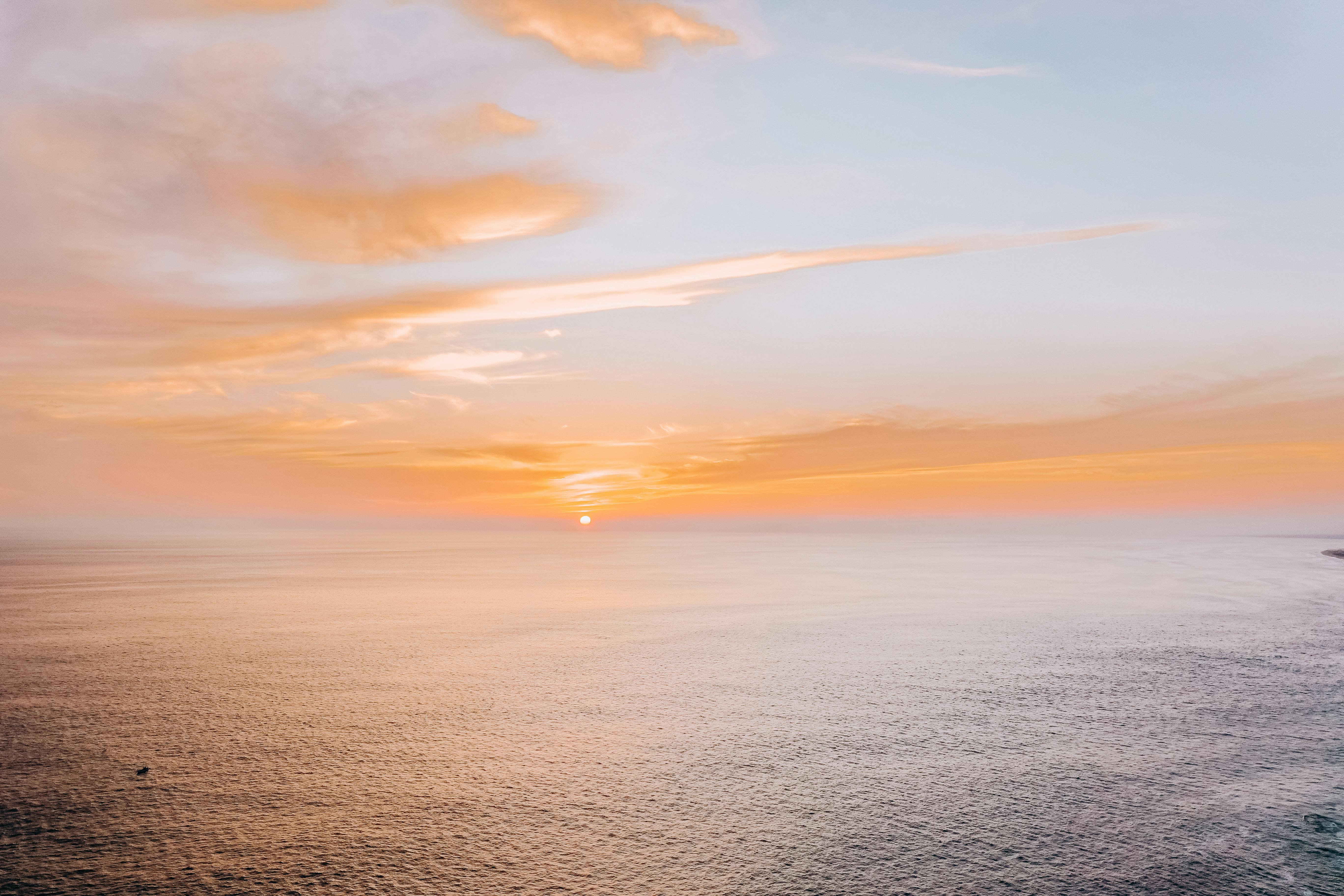 body of water under cloudy sky during sunset