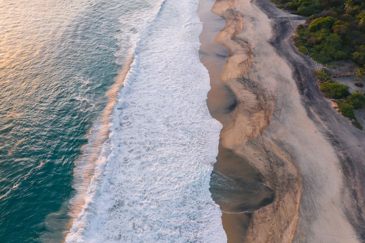 Aerial view of powerful Pacific waves breaking along a wild Oaxacan beach