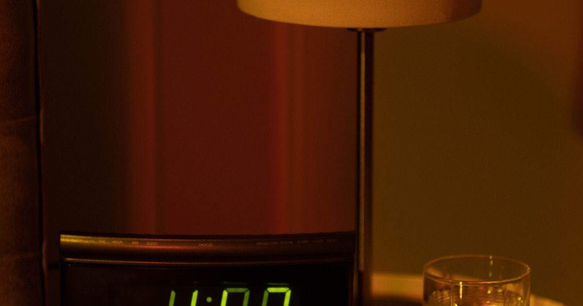 A dimly lit bedside table at night with a digital clock showing the early morning hours