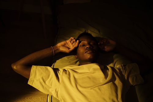 Free A man lying down in a cozy, warm-lit room, peacefully asleep during the night. Stock Photo