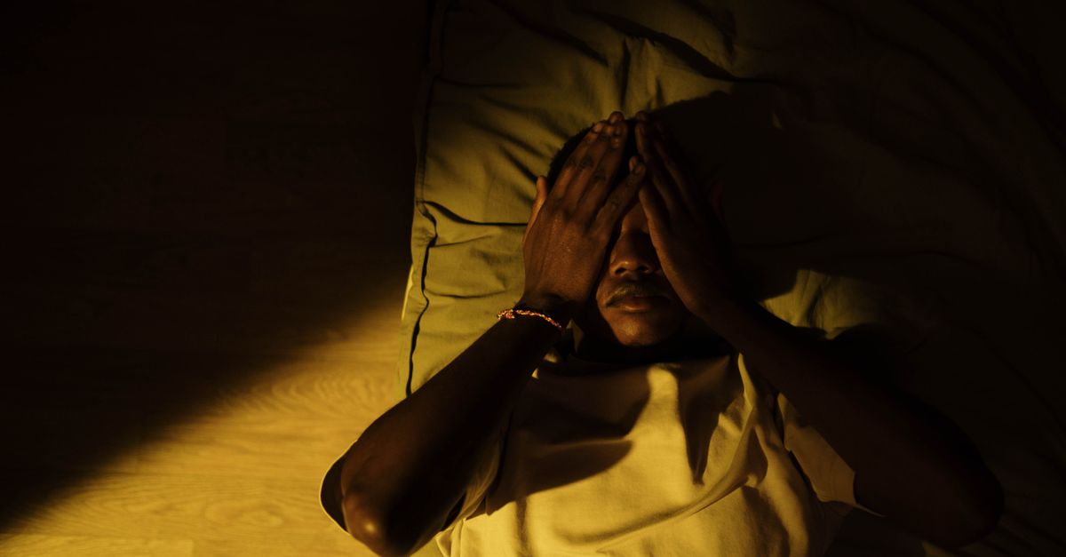 A man lying on the bed in a dark room