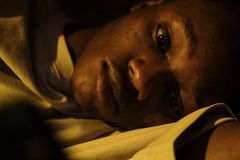 A young man lying awake in bed, depicting insomnia and sleeplessness.