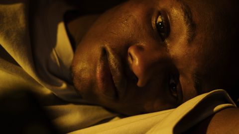 A young man lying awake in bed, depicting insomnia and sleeplessness.