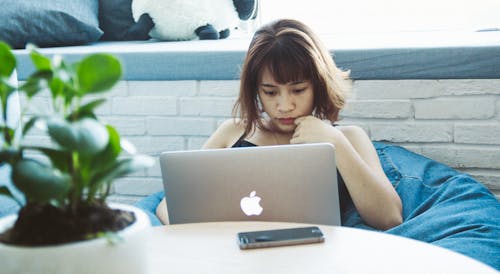 シルバーのmacbookを使用して黒いタンクトップの女性