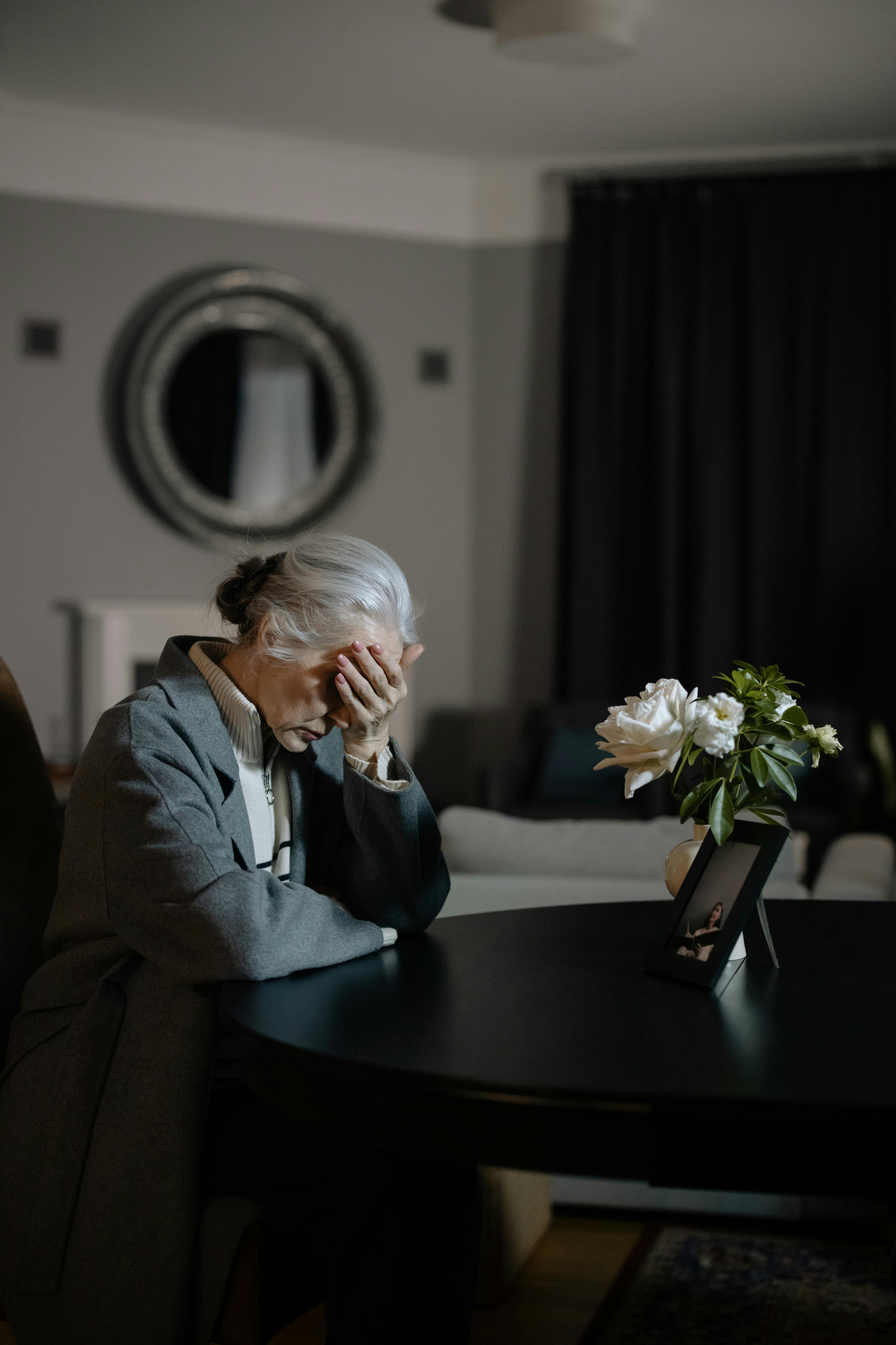 Senior woman grieving indoors at home, expressing deep emotion and loss.