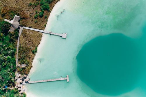Free Stunning aerial view of a tropical beach with turquoise water, docks, and lush vegetation. Stock Photo