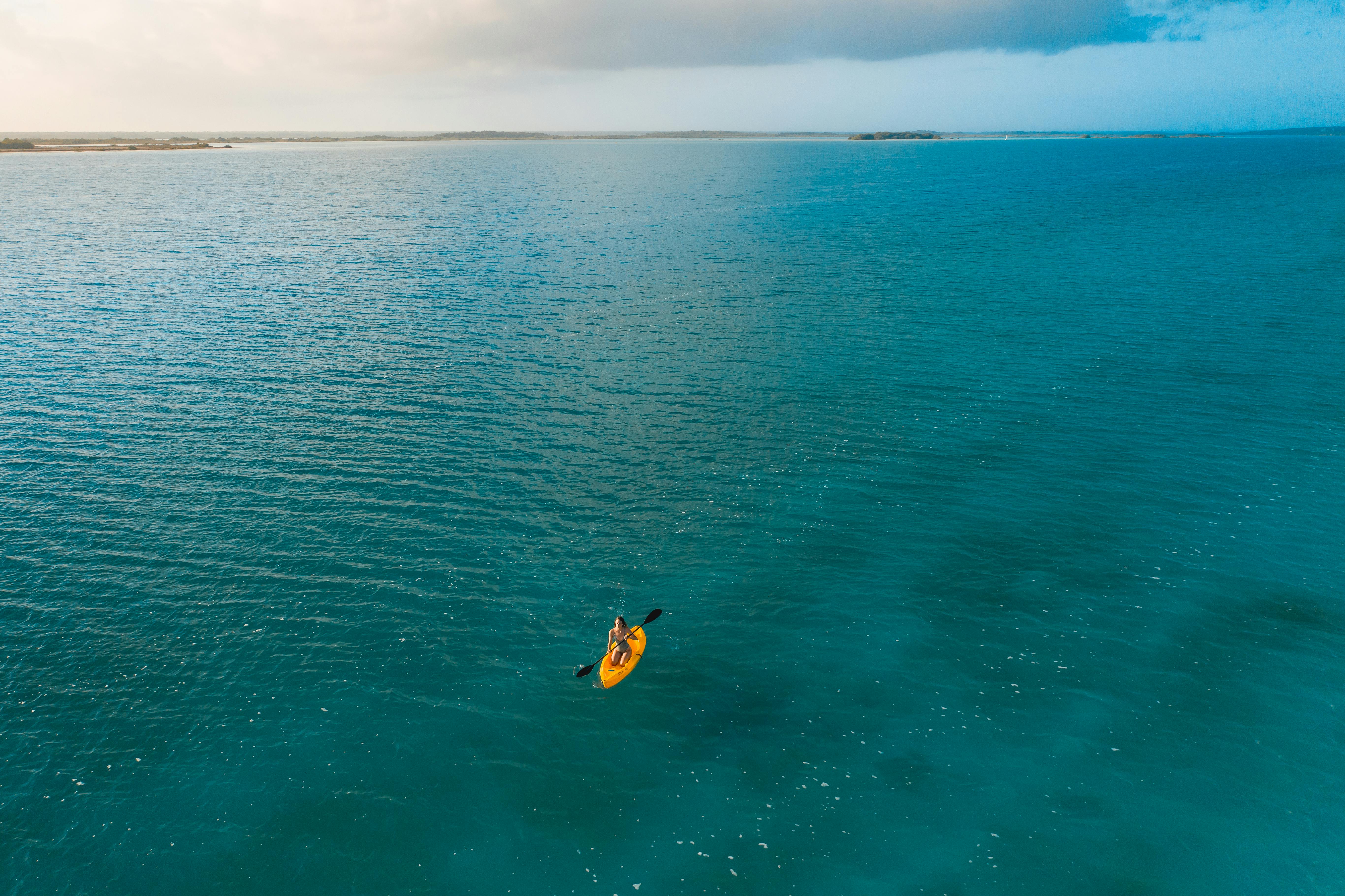 person in yellow and black wetsuit surfing on blue sea