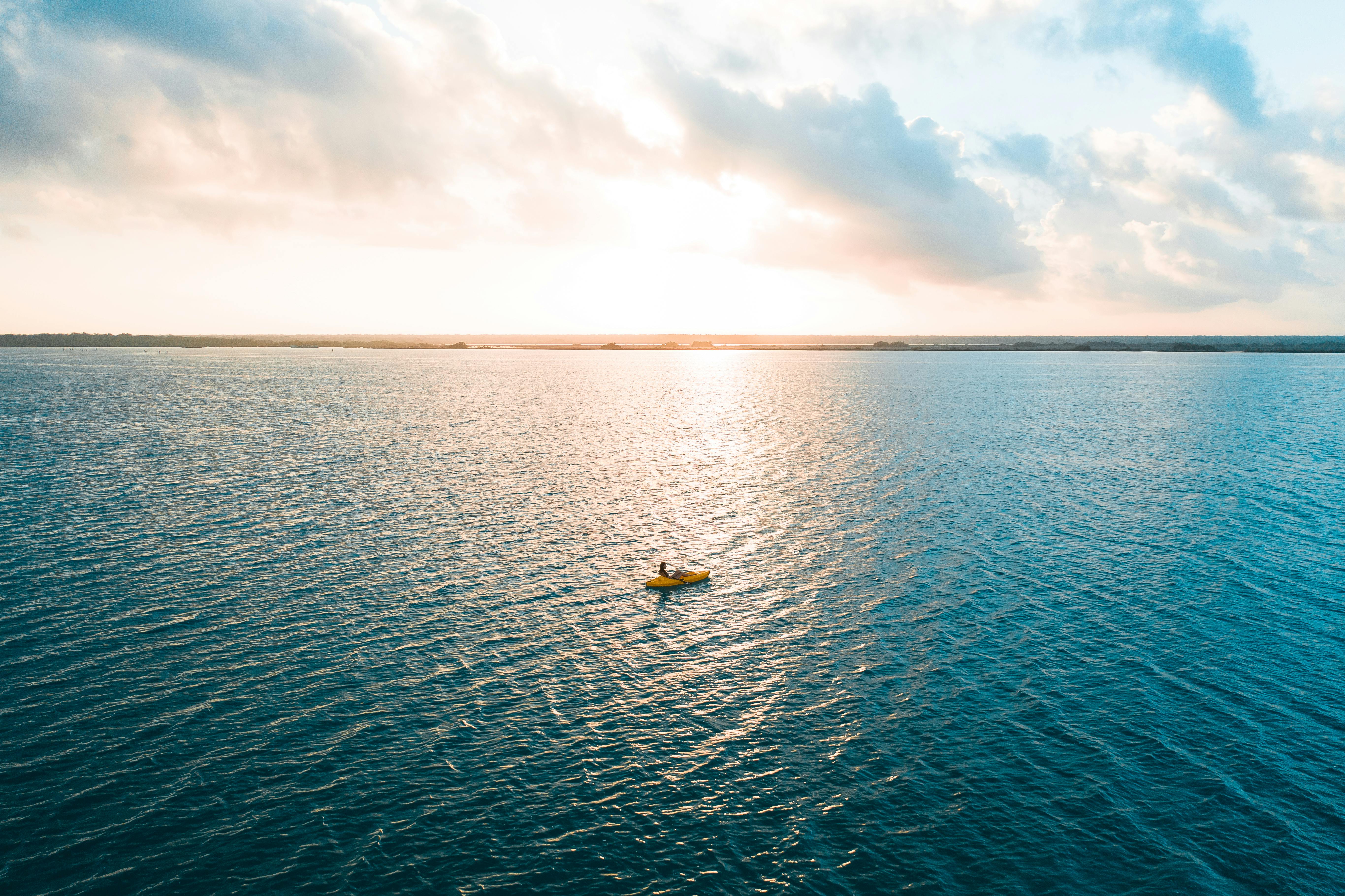 yellow boat on blue sea under white clouds