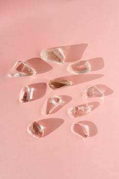 An artistic arrangement of clear quartz crystals casting shadows on a pink surface.