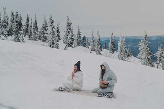 Two people meditate in a serene snowy pine forest, embracing tranquility and mindfulness.