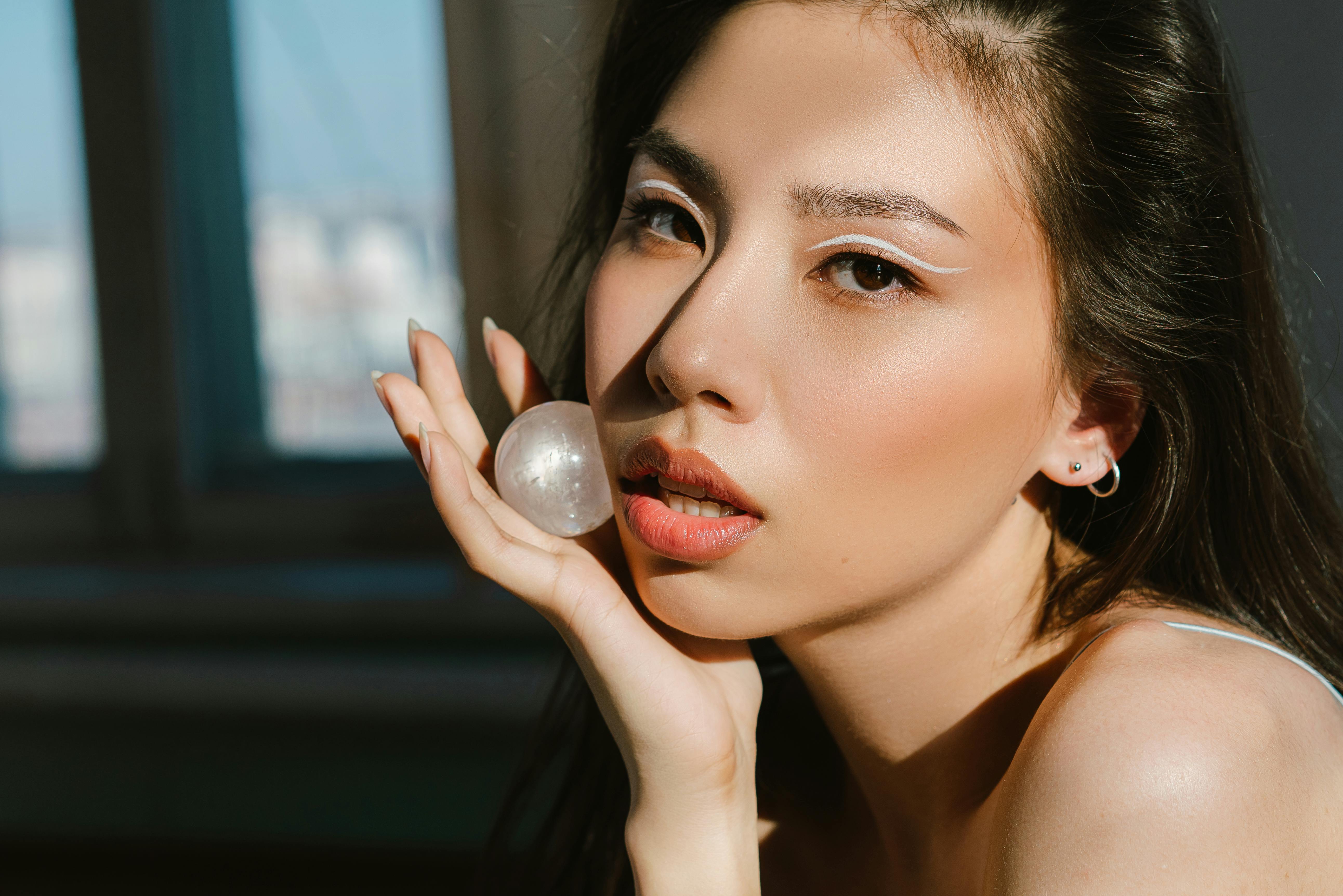 Close-up portrait of a woman holding a gemstone, highlighting her elegant features.