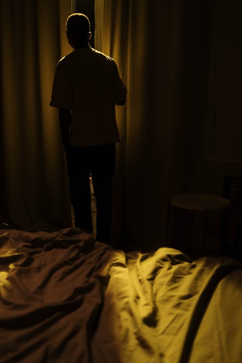 Silhouette of Man Standing by Bed