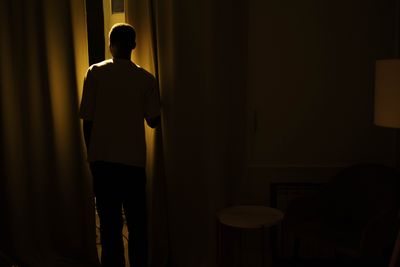 A figure lit low in a dark room, photo by cottonbro studio on Pexels