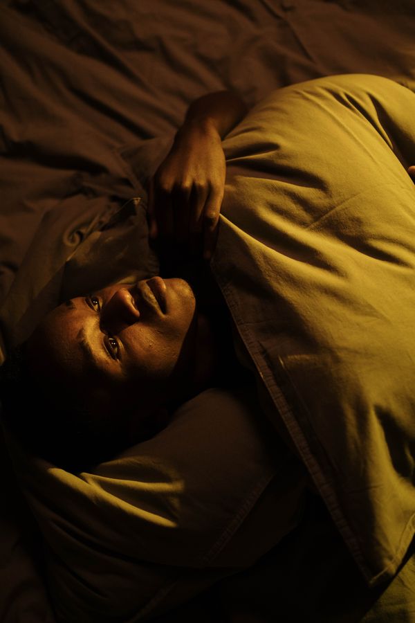 A man resting under a duvet in warm low light — photo by cottonbro studio on Pexels