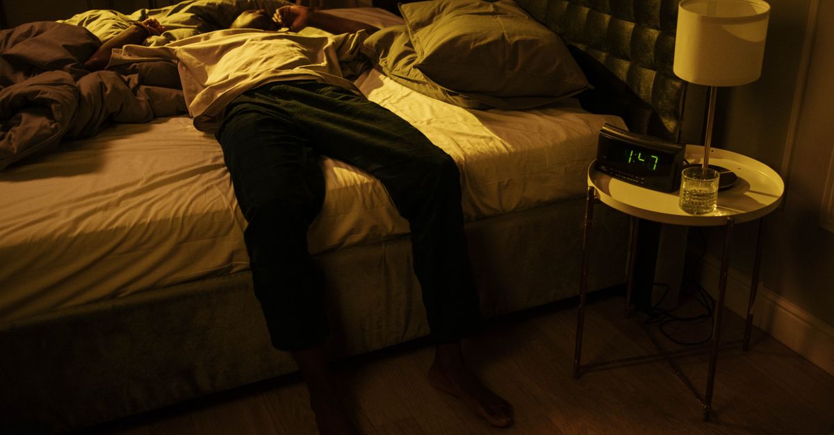 Person staring at phone in bed with tired eyes, clock showing 2 AM