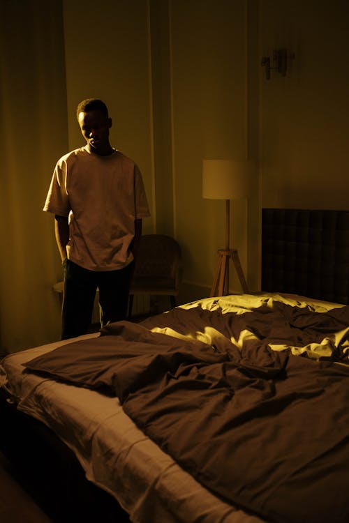 Free A Man Thinking while Standing Beside the Bed Stock Photo