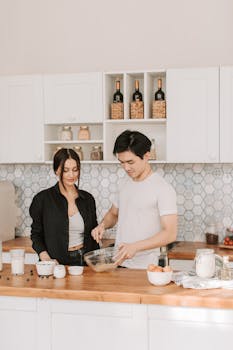 Asian man and woman preparing food together in a stylish kitchen setting.