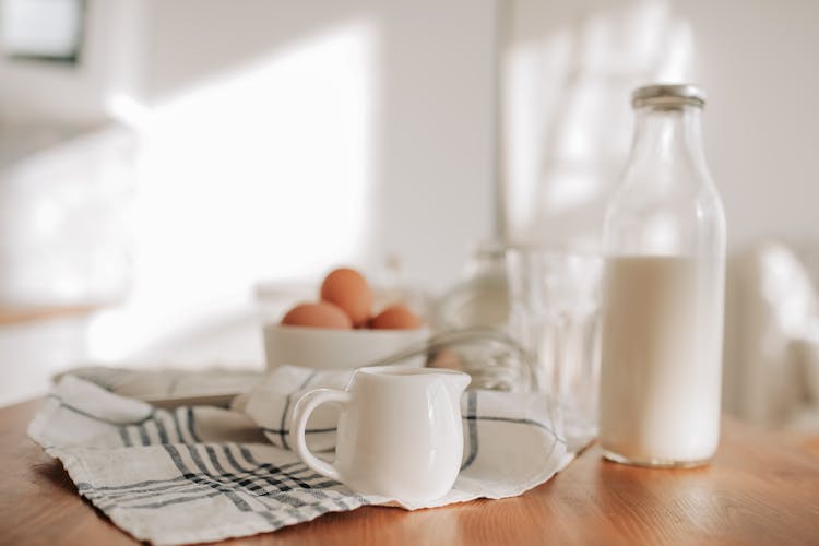 
A Close-Up Shot Of A Porcelain Creamer And A Bottle Of Milk