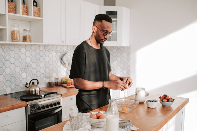 
A Man In A Black Shirt Cracking An Egg