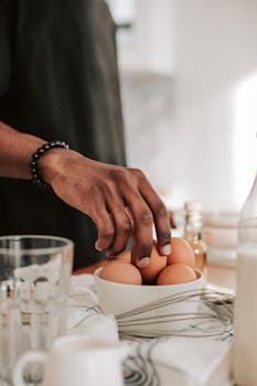 Close-up of a man selecting eggs from a bowl, emphasizing culinary preparation.