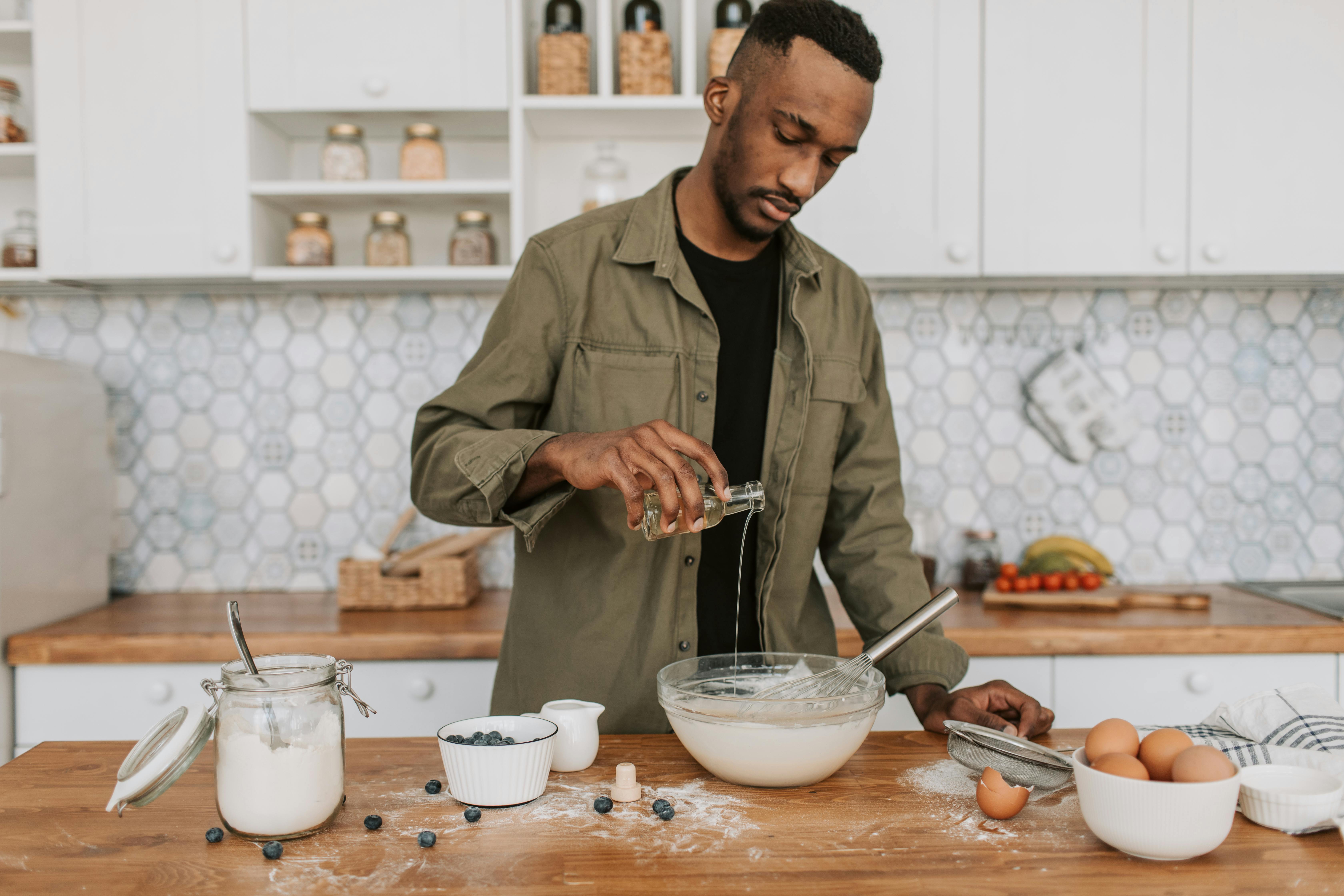 African American man pouring syrup while preparing food in a modern kitchen.